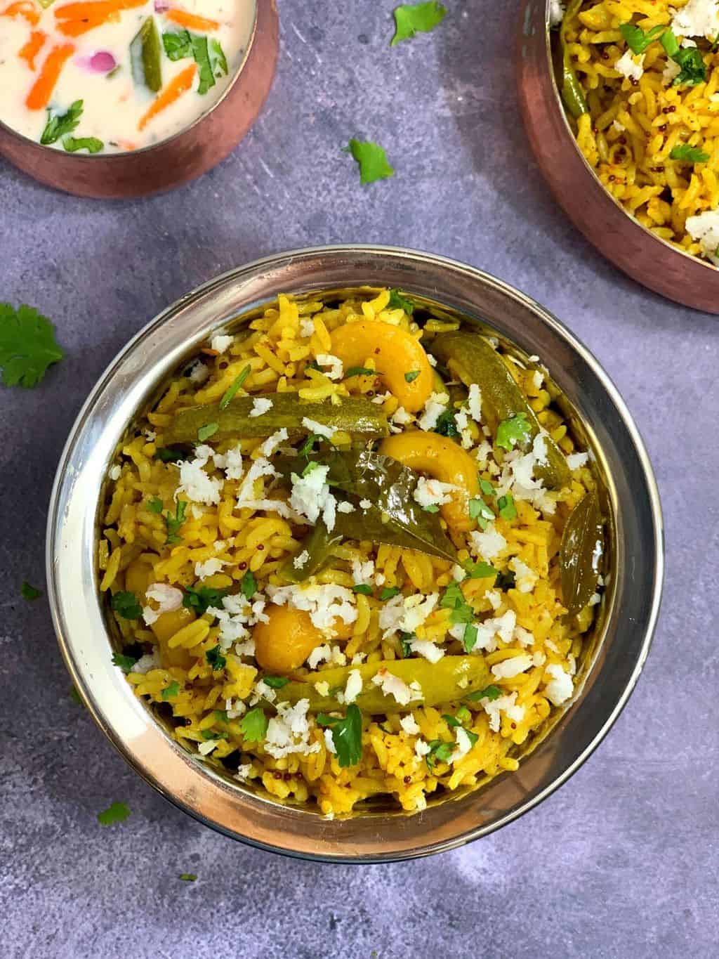 Tendli Masale bhaat in a copper bowl with raita on side