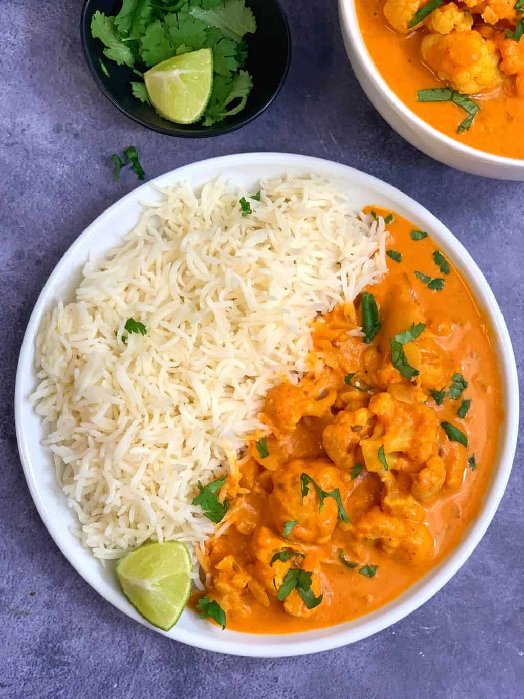 coconut cauliflower curry served in a plate along with basmati rice and lemon wedge on top