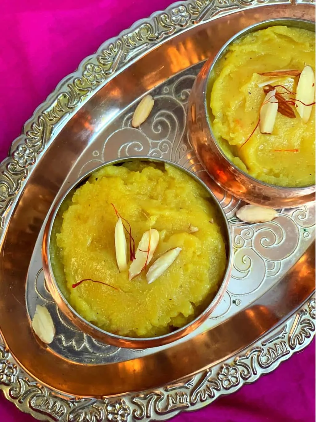 badam halwa preparato con farina di mandorle servito in due ciotole guarnito con mandorle e zafferano 