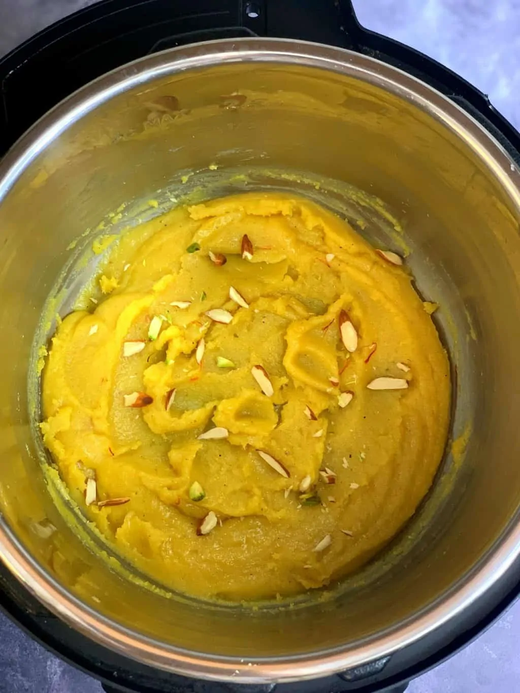 badam halwa en inserto de olla instantáneo adornado con almendras y hebras de azafrán