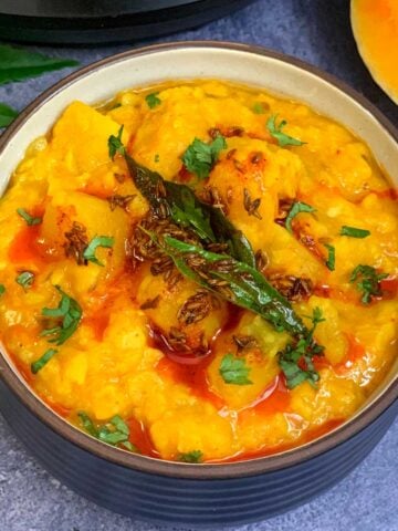 Butternut Squash Dal served in a bowl topped with tempering and a piece of butternut squash on the side