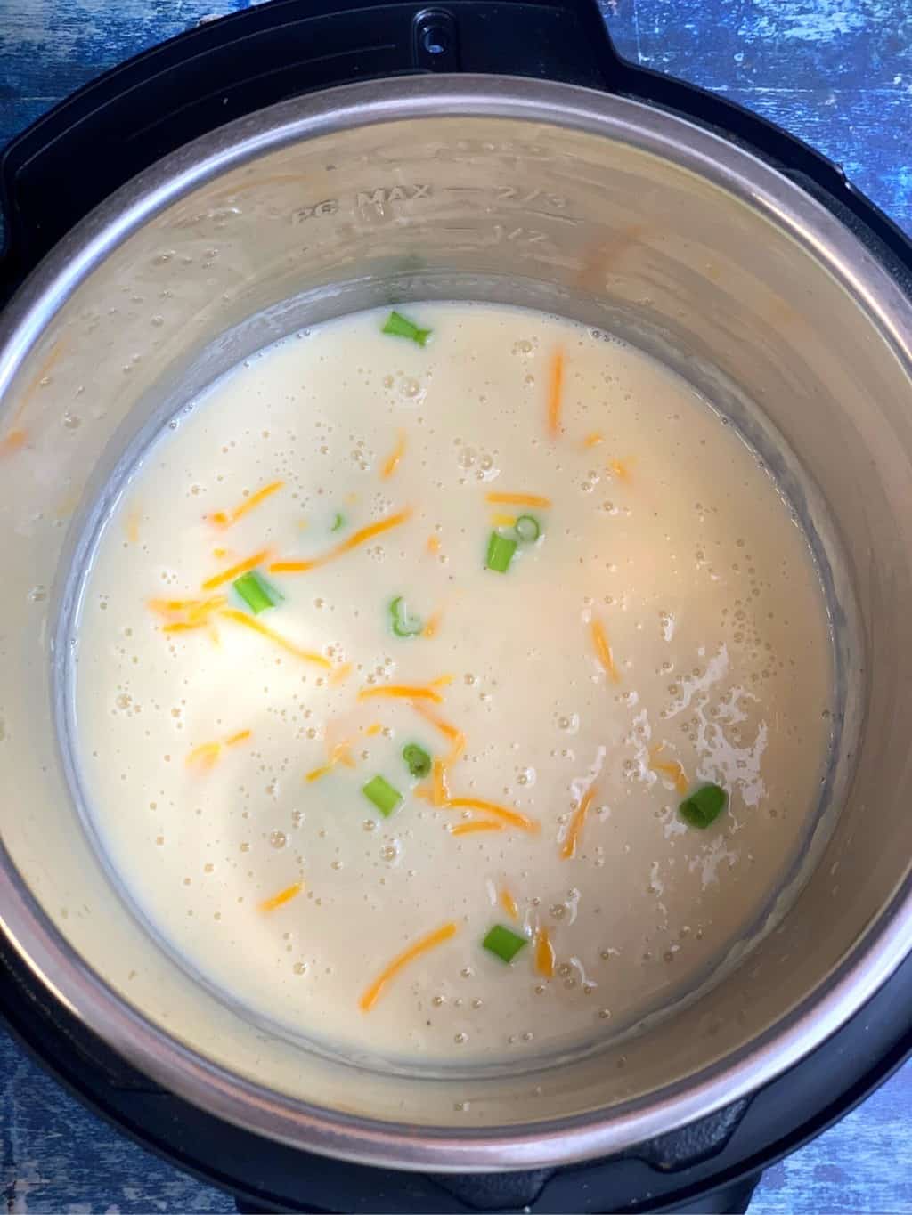 cauliflower soup in instant pot insert garnished with cheese and green onions