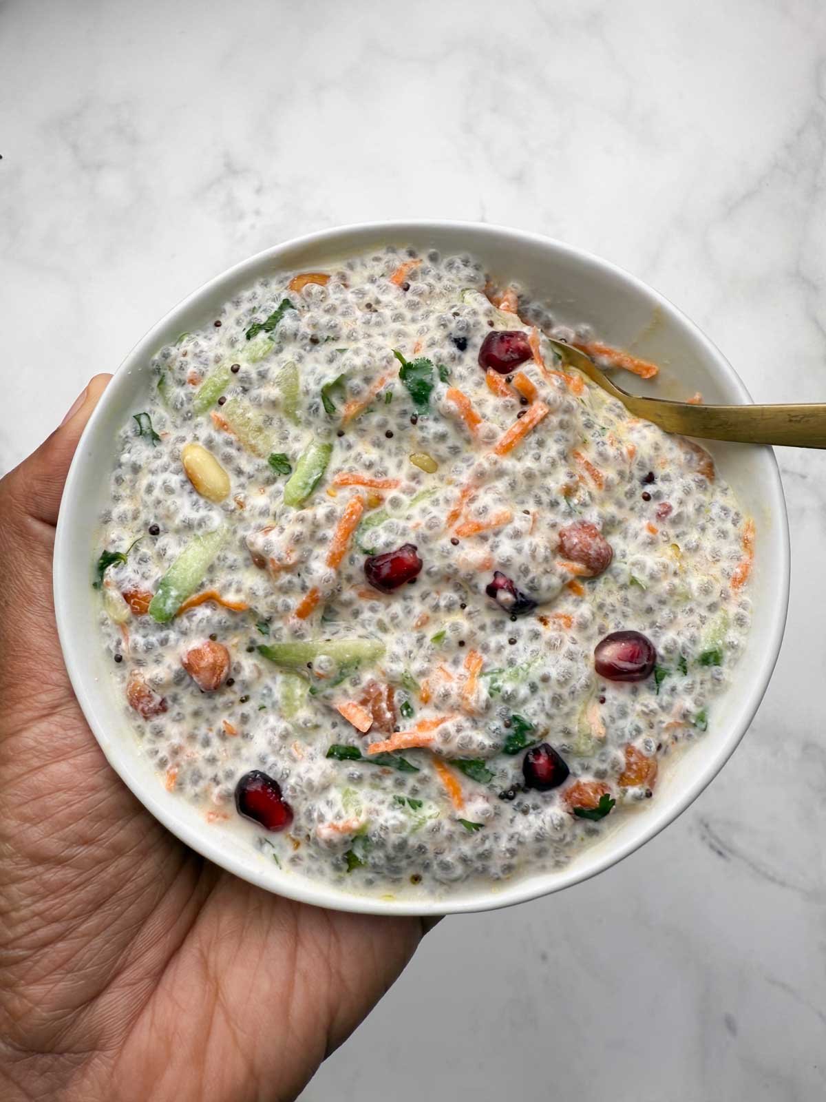 Me holding a bowl of savory chia curd with a golden spoon in it.