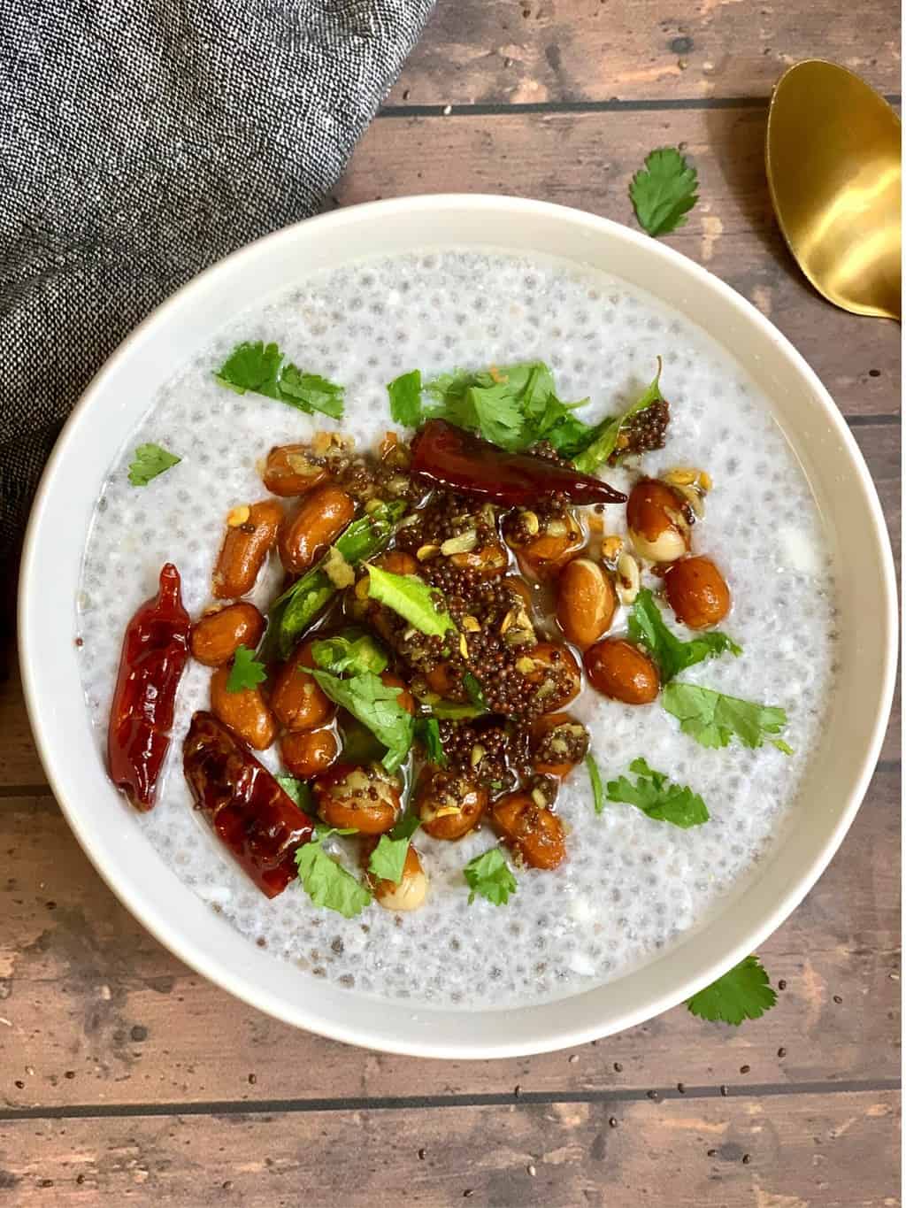 chia seeds curd rice served in a white bowl and tempered with spices with spoon on side