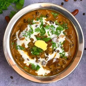 Dal Makhani served in a steel bowl garnished with cream butter and cilantro