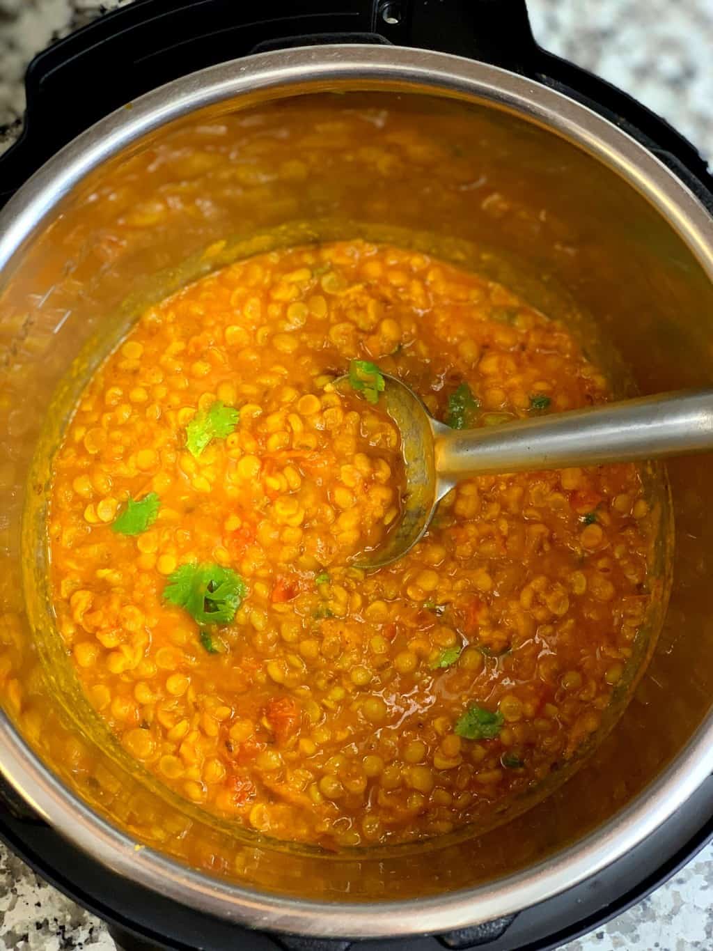 chana dal in the instant pot insert with a spoon garnished with cilantro 