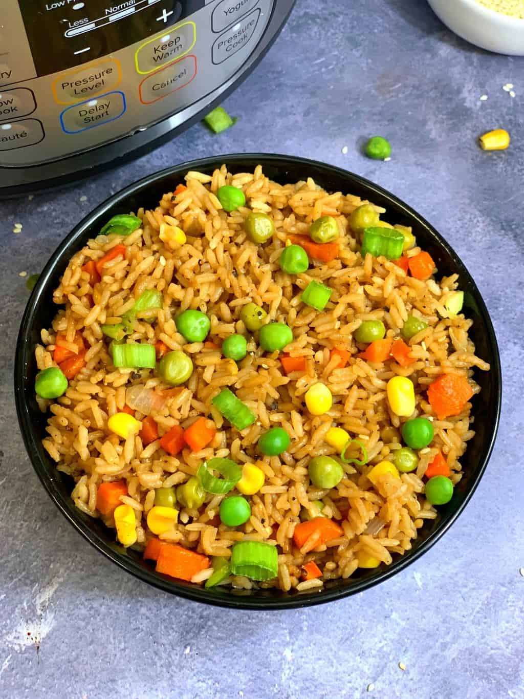 vegetable fried rice served in a bowl with instant pot on the side