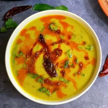 Palak Kadhi served in a bowl with tempering on the top with side of a rice