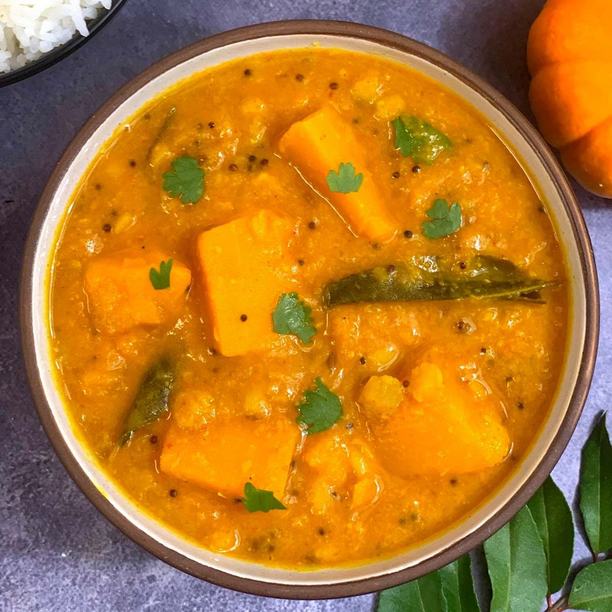 Pumpkin Sambar made of lentils and pumpkin served in a bowl with cooked rice on side