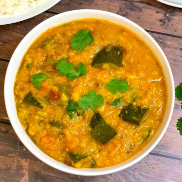 zucchini dal served in a bowl garnished with cilantro and side of steamed rice