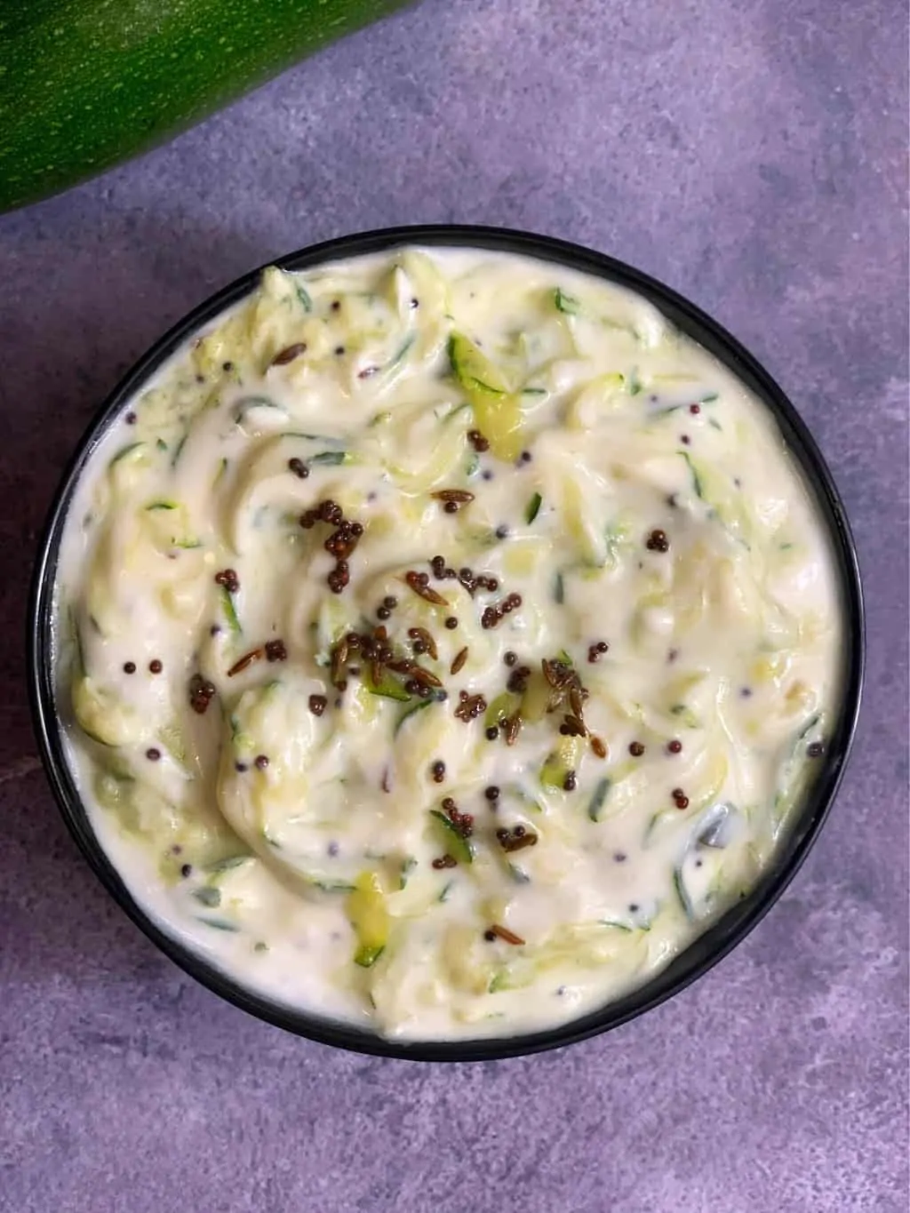 zucchini raita served in a bowl with tempering on the top