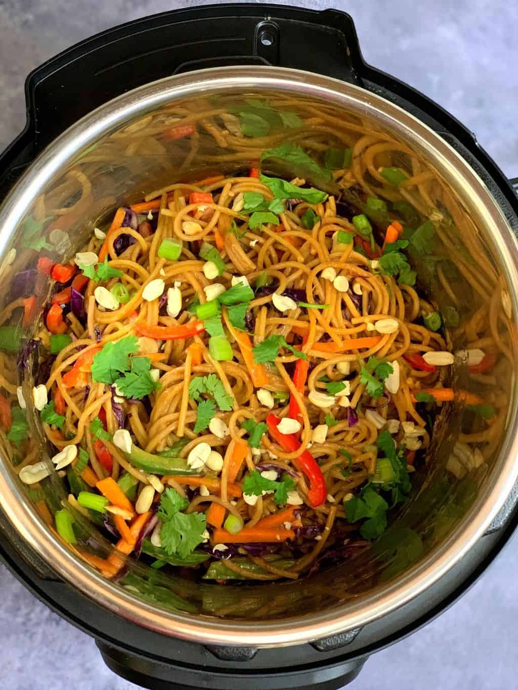 thai peanut noodles in the instant pot insert garnished with roasted peanuts and cilantro