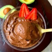 chocolate avocado mousse served in a glass bowl garnished with strawberry and avocado on side