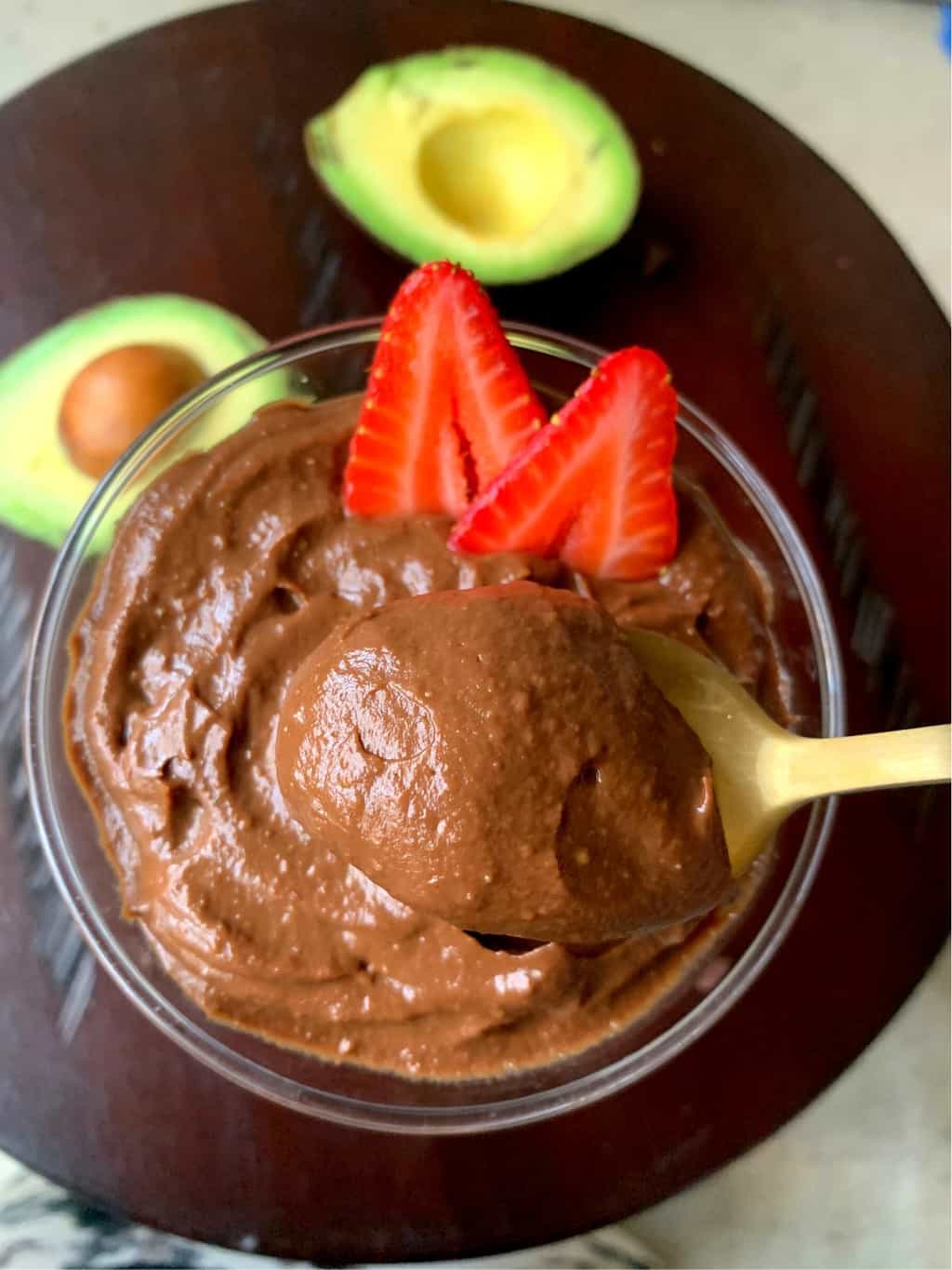 avocado mousse in spoon with avocados in the side