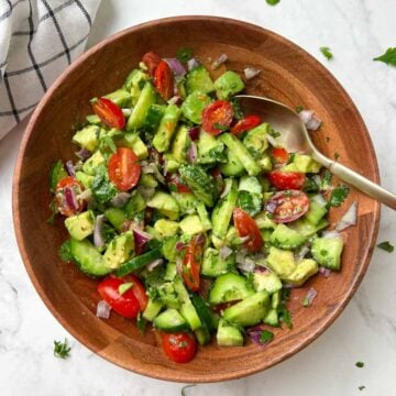 avocado cucumber salad served in a bowl with a spoon