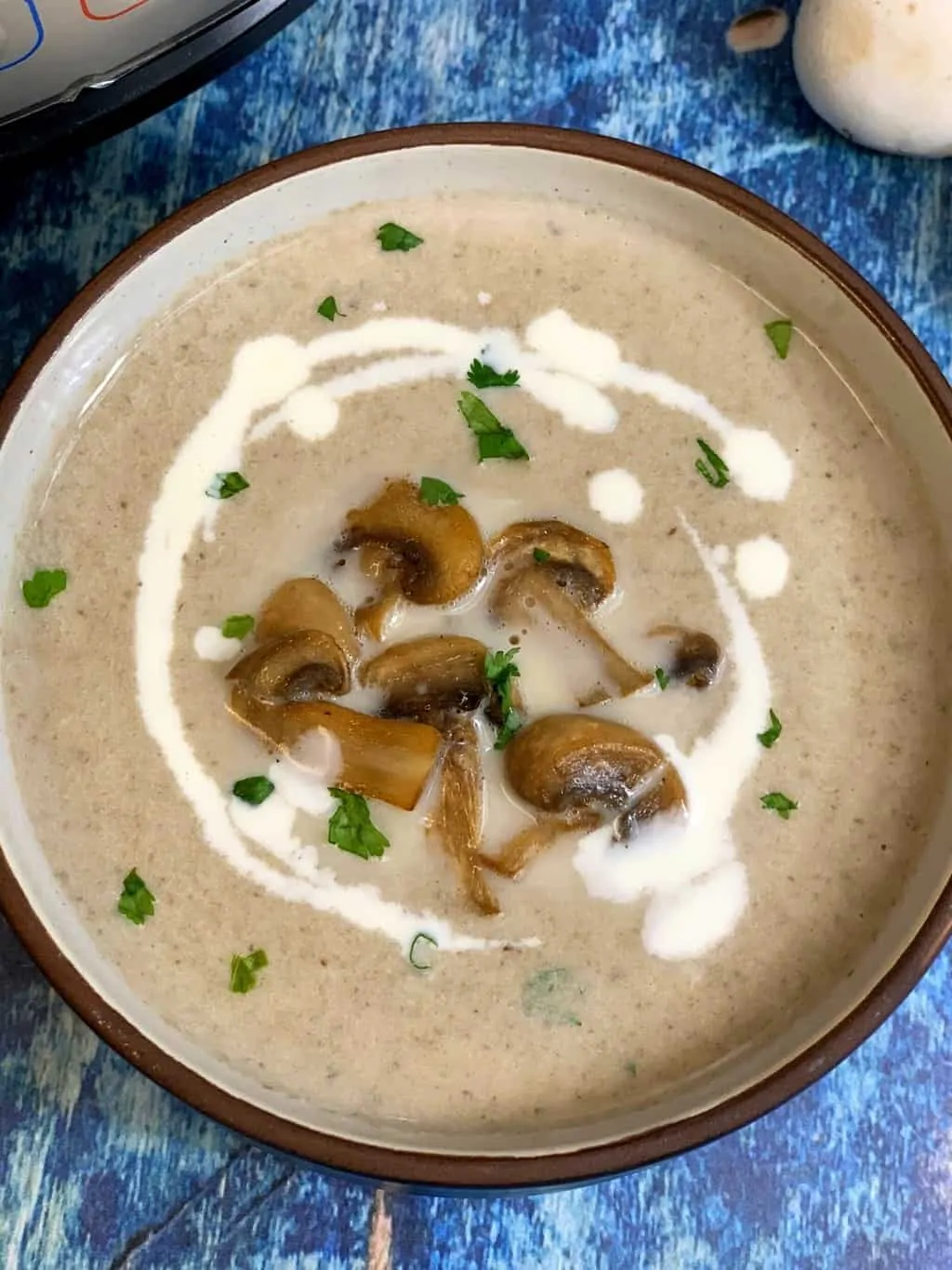 creamy mushroom soup served in a bowl topped with sauteed mushrooms cilantro and cream