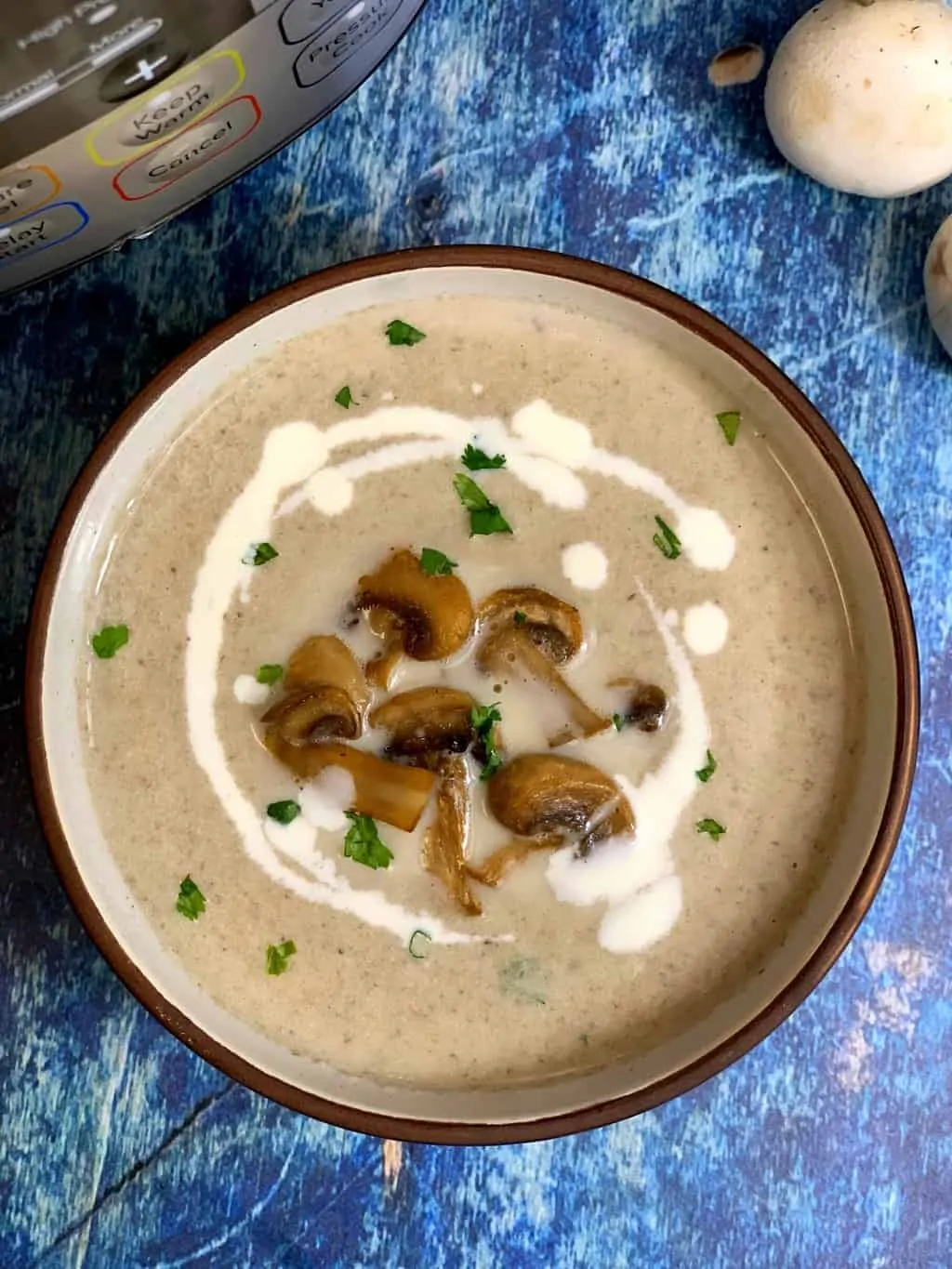 creamy mushroom soup served in a bowl garnished with cream sauteed mushrooms and cilantro