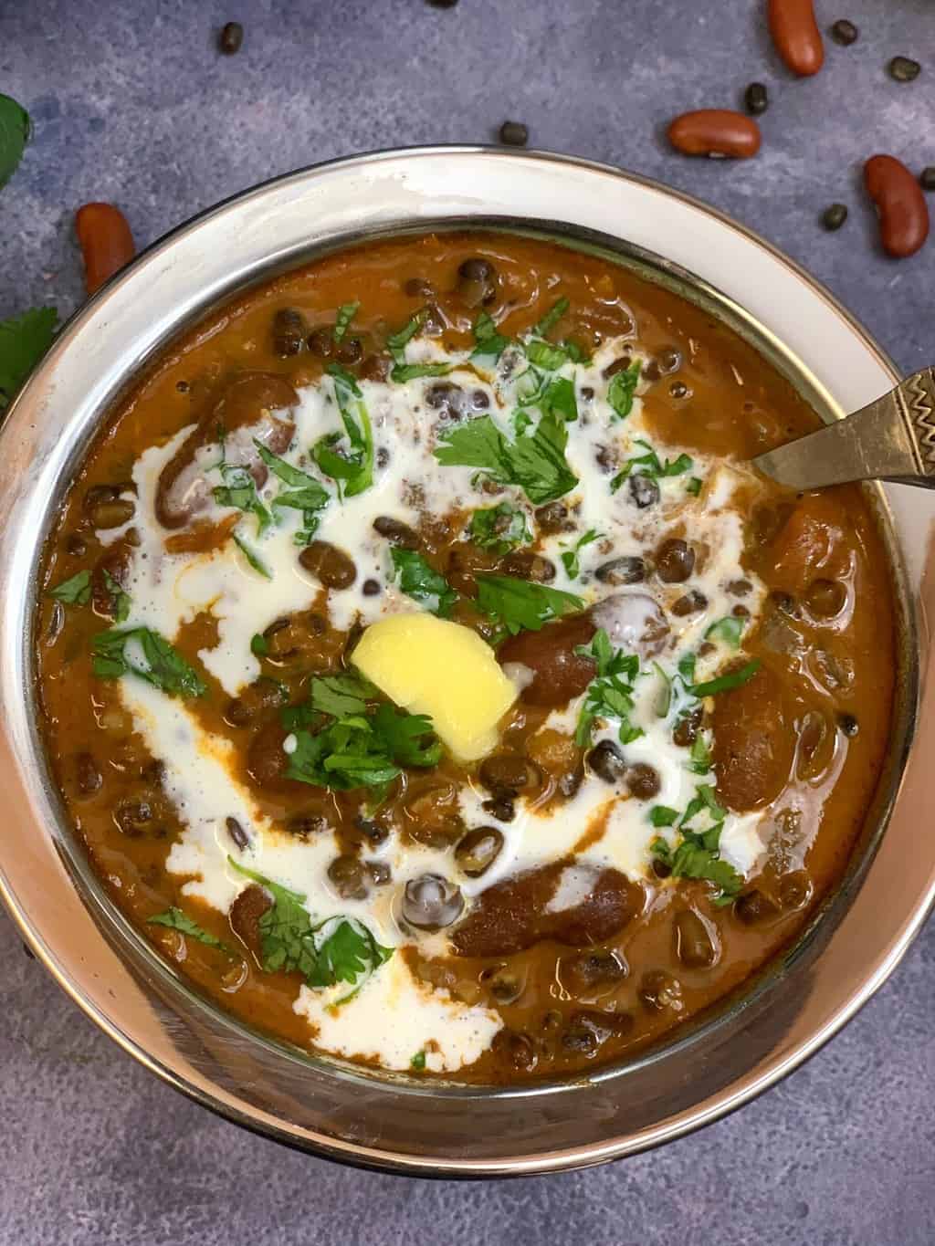 dal makhani served in a bowl with a spoon garnished with cream cilantro and butter