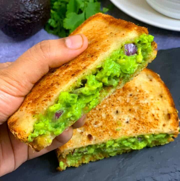 Grilled guacamole avocado sandwich held by a hand