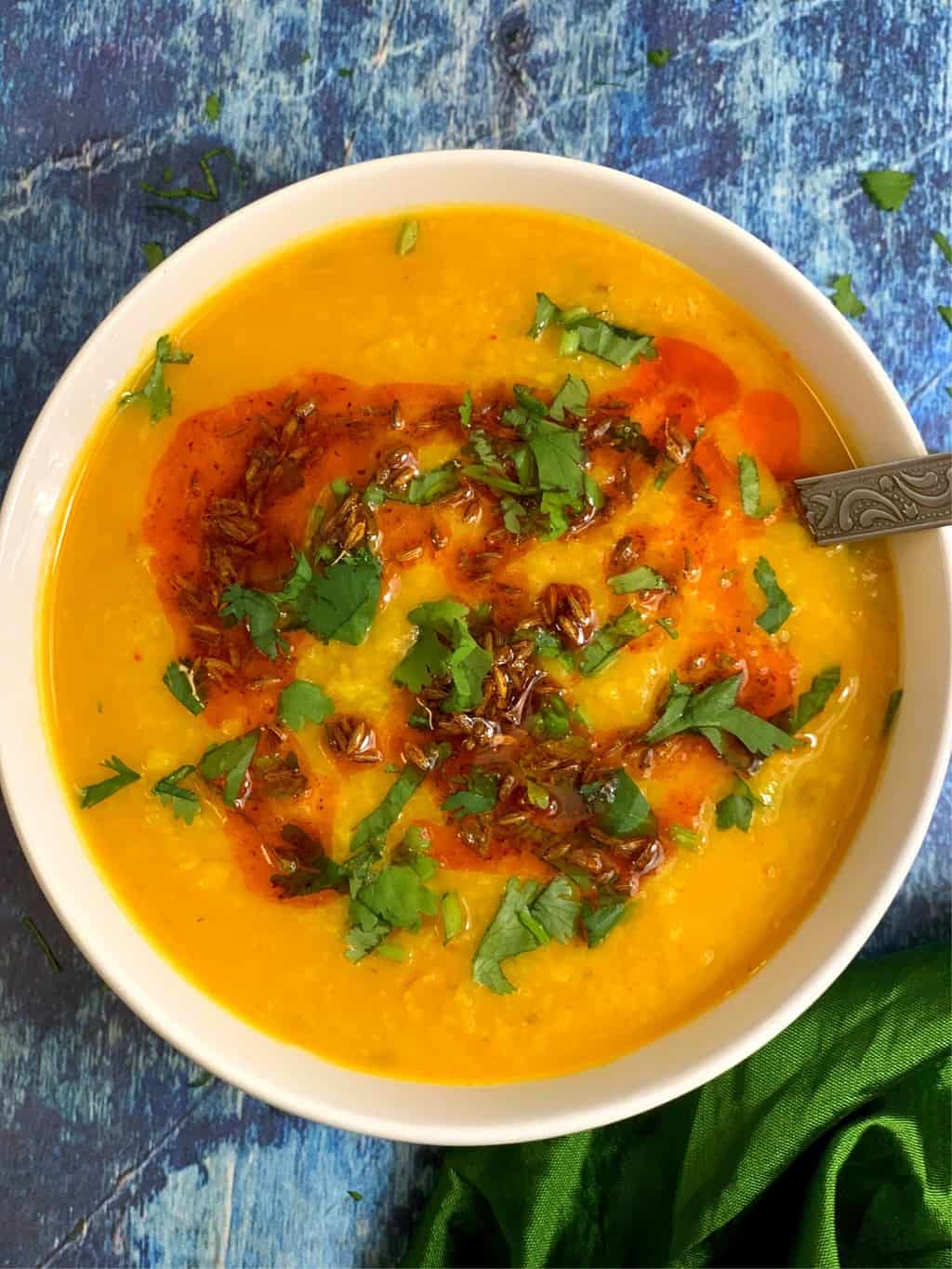 moong dal tadka served in a white bowl with tempering on the top garnished with cilantro