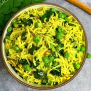 moringa/drumstick leaves rice served in a bowl and drumstick leaves ,peas and cinnamon stick on side