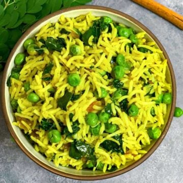 moringa/drumstick leaves rice served in a bowl and drumstick leaves ,peas and cinnamon stick on side