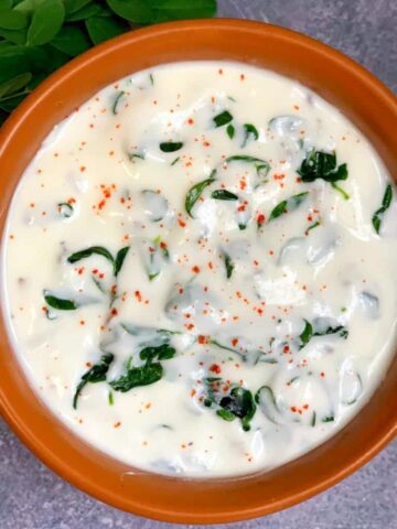 Moringa leaves Raita served in a bowl with drumstick leaves on the side