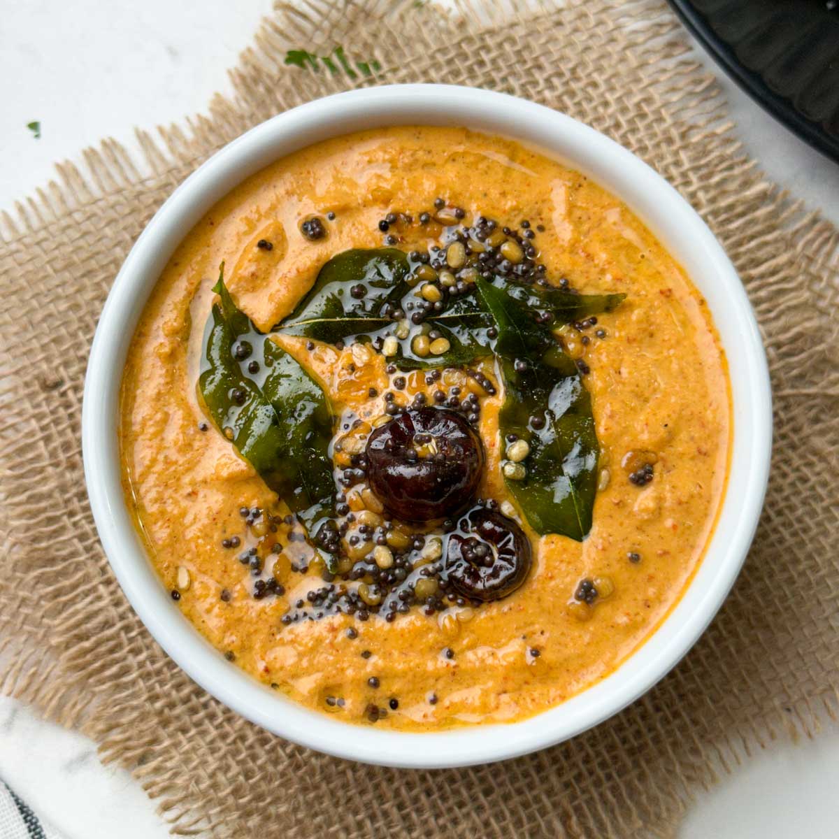 peanut chutney recipe served in a white bowl with idli and vegetable sambar on the side