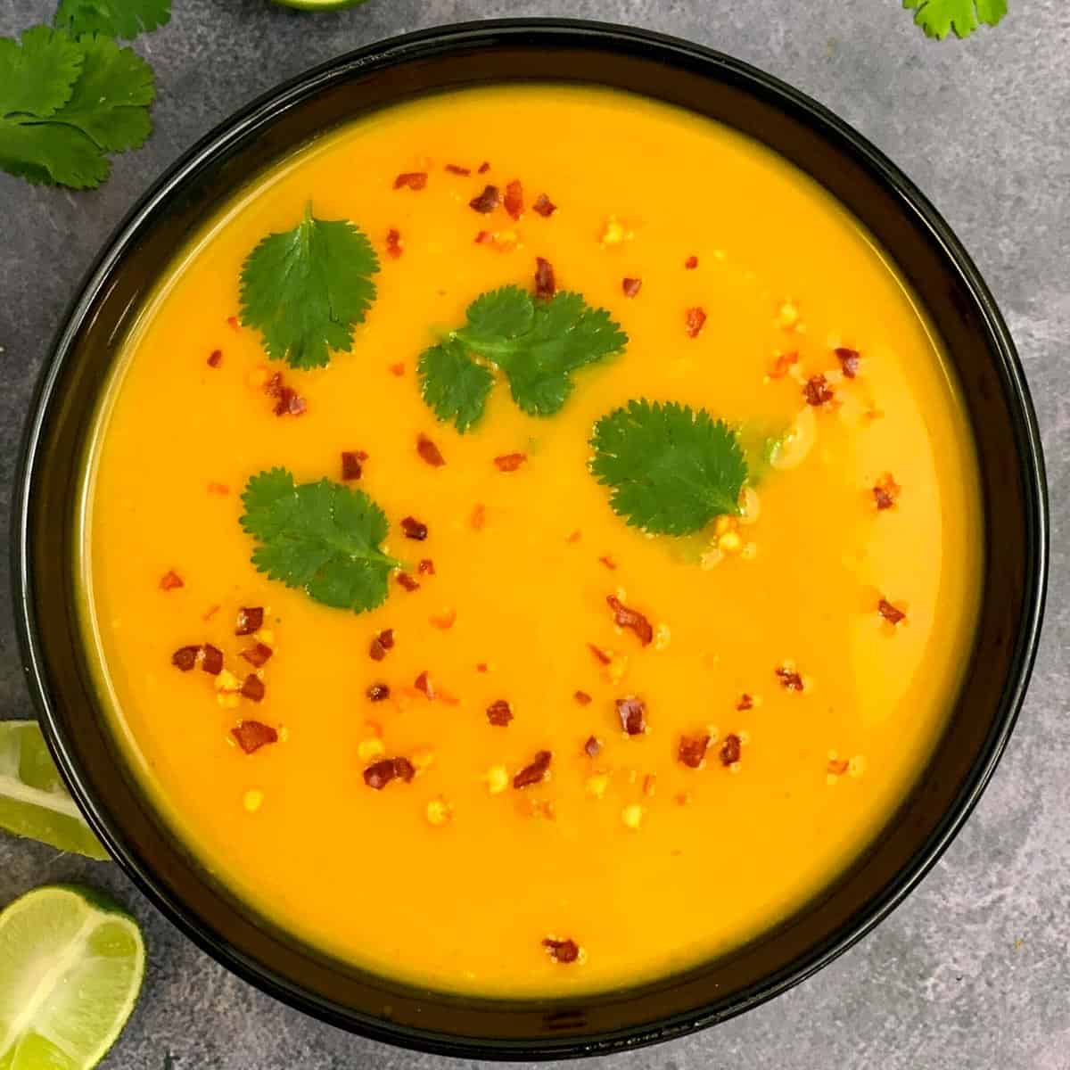 Thai Curried Pumpkin Soup served in a soup bowl garnished with red chilli flakes and cilantro