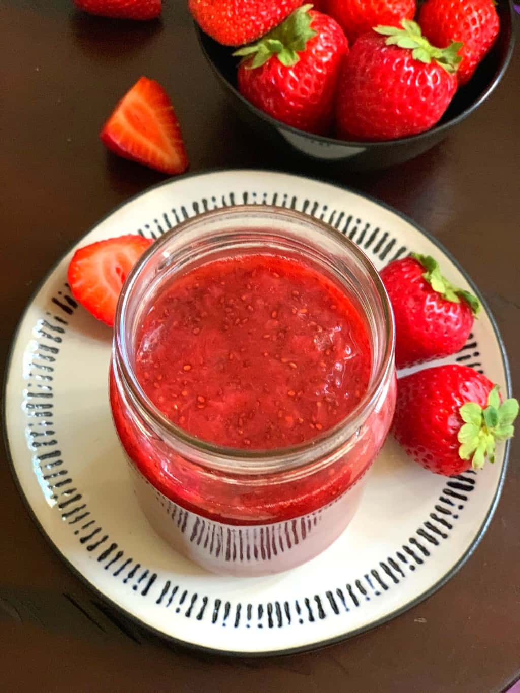 strawberry jam served in a mason jar with fresh strawberries on the side