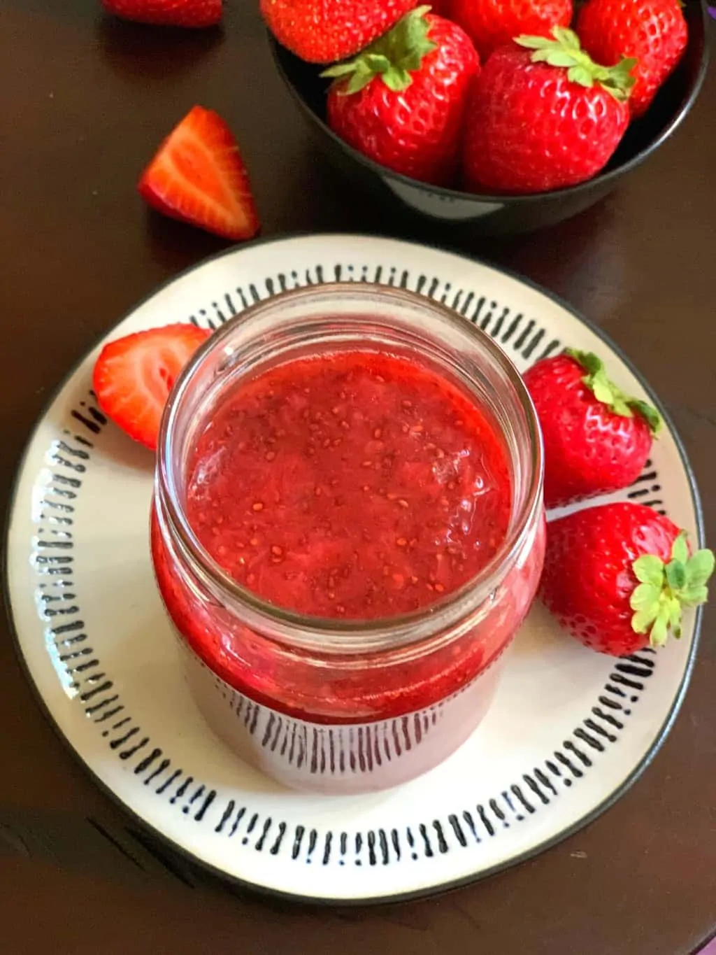 strawberry jam served in a mason jar with fresh strawberries on the side