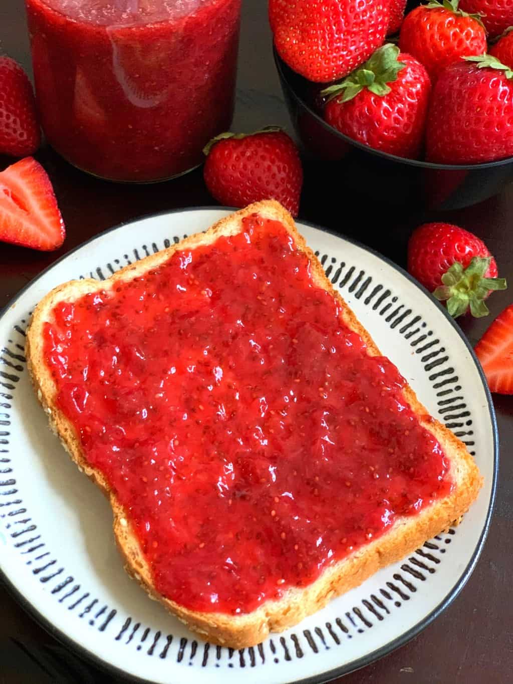 strawberry jam spread on the bread with strawberries on the side