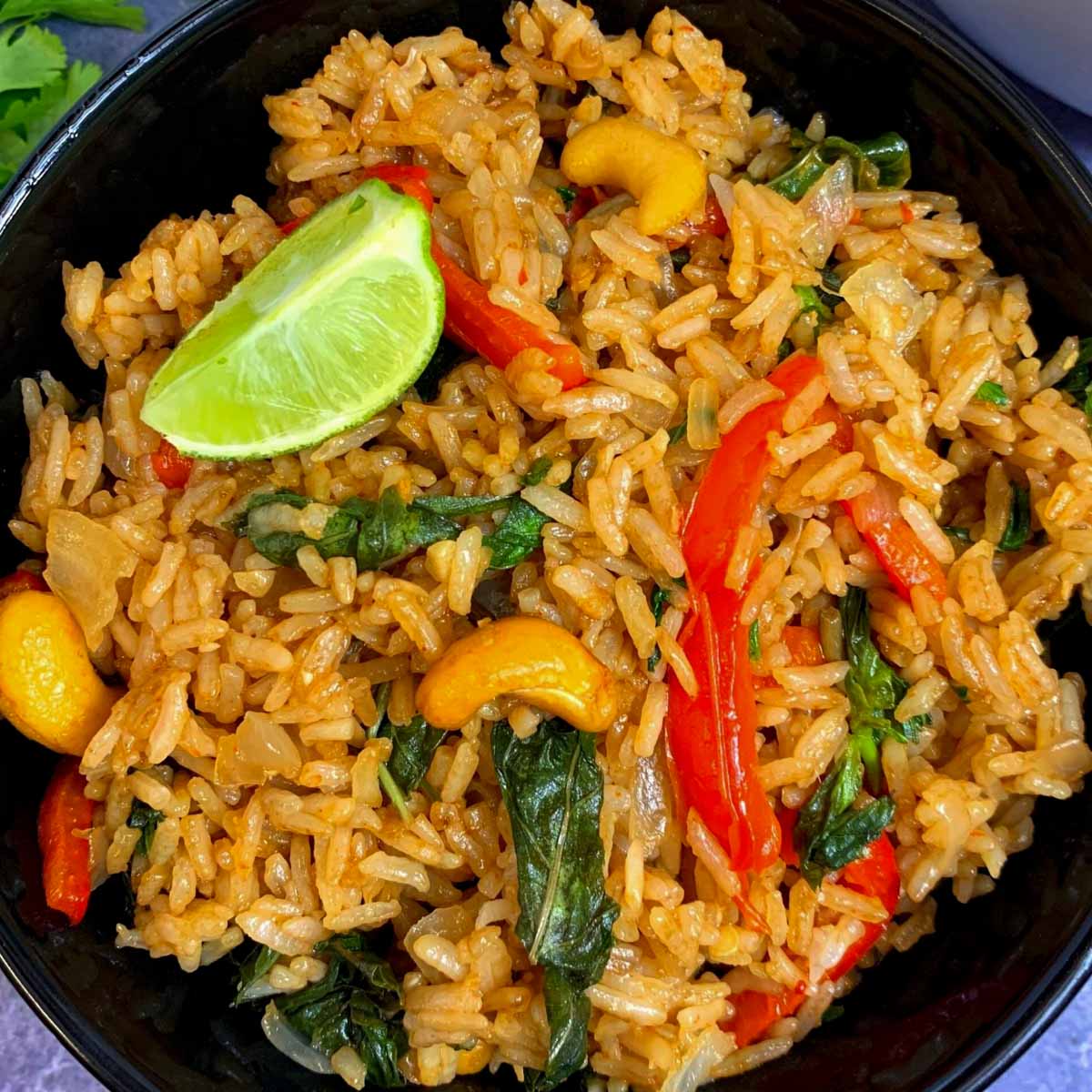 Spicy Thai Basil Fried Rice served in a black bowl with lemon wedge on top