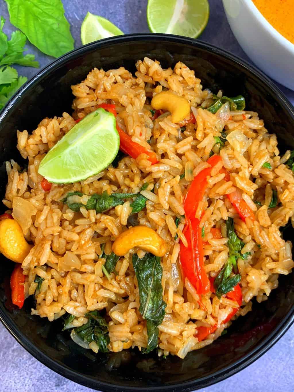 thai basil fried rice made in instant pot served in a black bowl with thai red curry and lemon on side