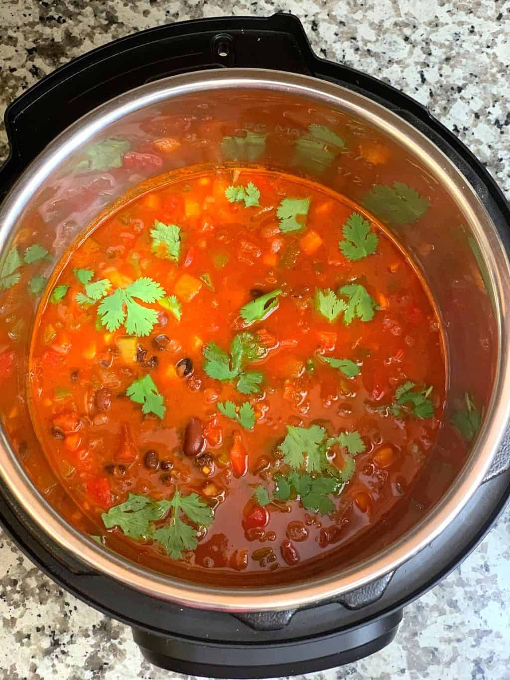 vegetarian chili in instant pot insert garnished with cilantro