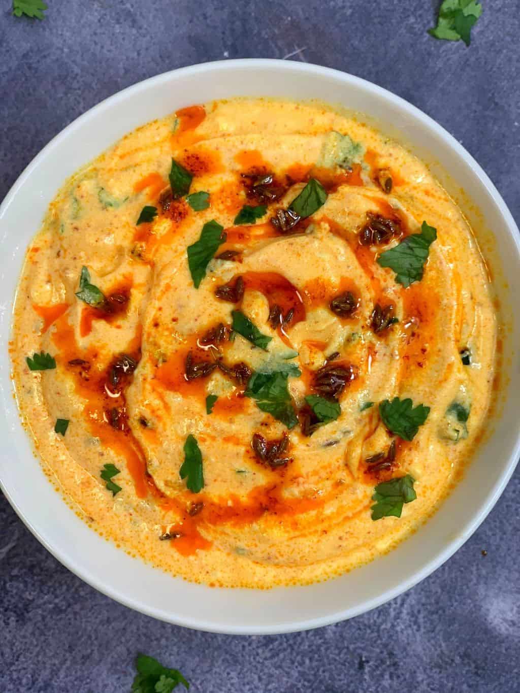 dahi tadka (dahi tikhari) served in a bowl with tempering on top and garnished with cilantro