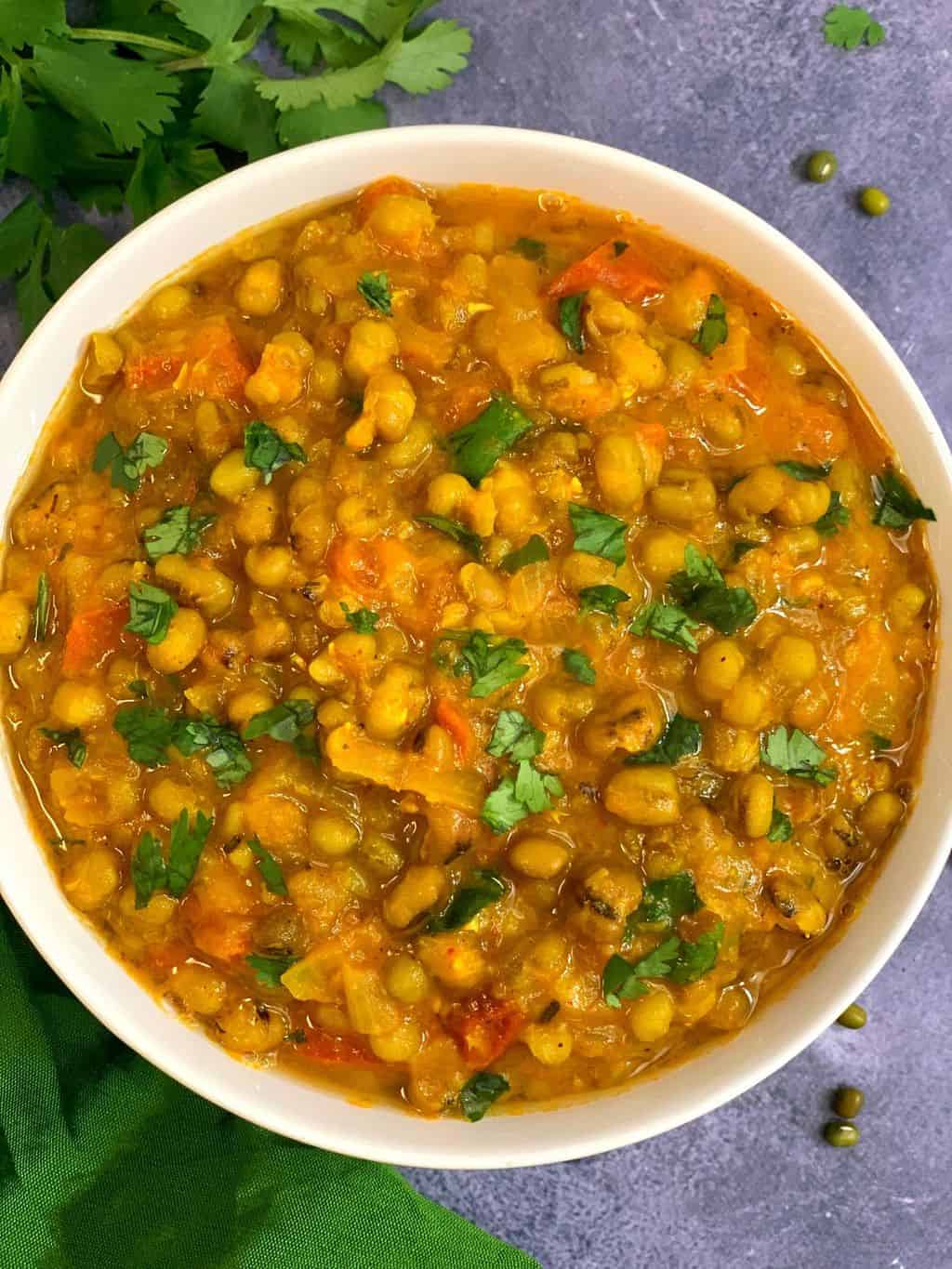 whole green moong dal made in the instant pot served in a white bowl and cilantro on side