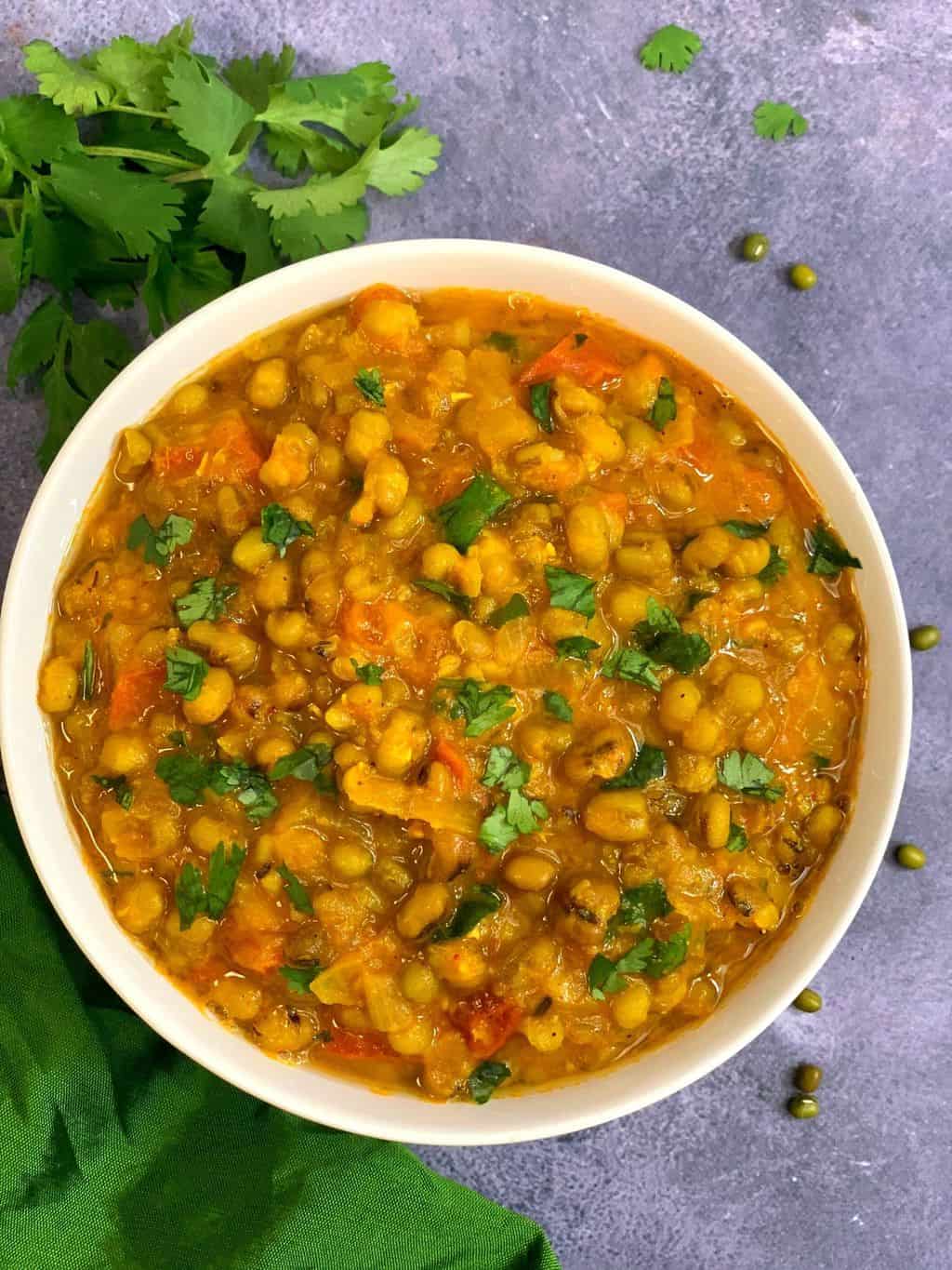 whole green moong dal/Mung Bean Curry served in a bowl garnished with cilantro