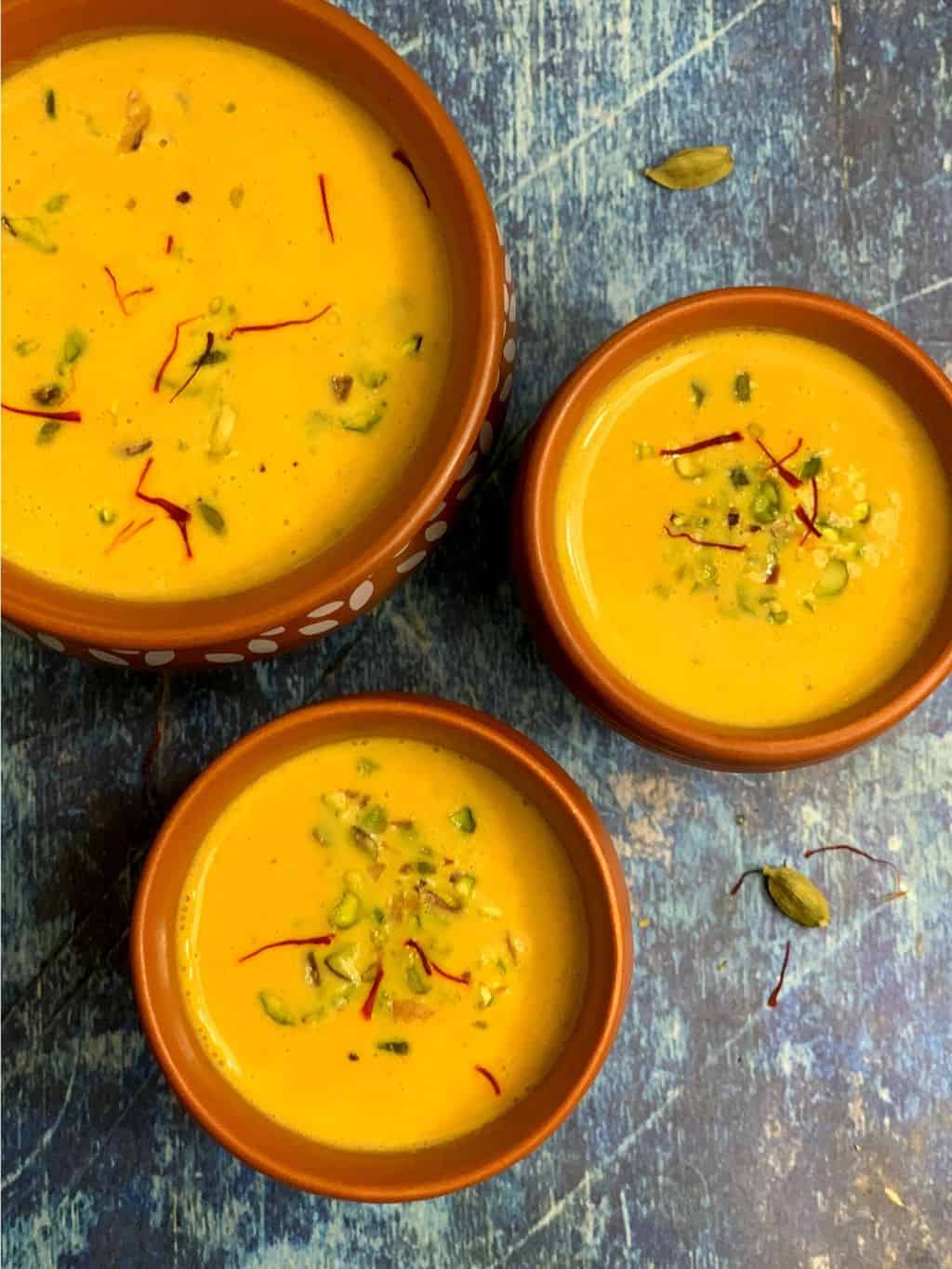 carrot kheer served in serving bowls garnished with nuts and saffron 