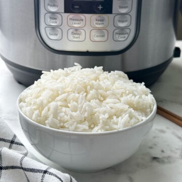 Fluffy jasmine rice in a white bowl and instant pot on the behind