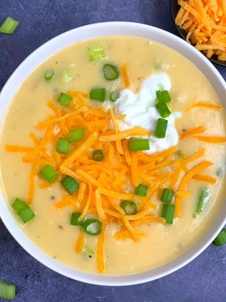 cheesy instant pot potato soup served in a bowl garnished with cream cheddar cheese and green onions