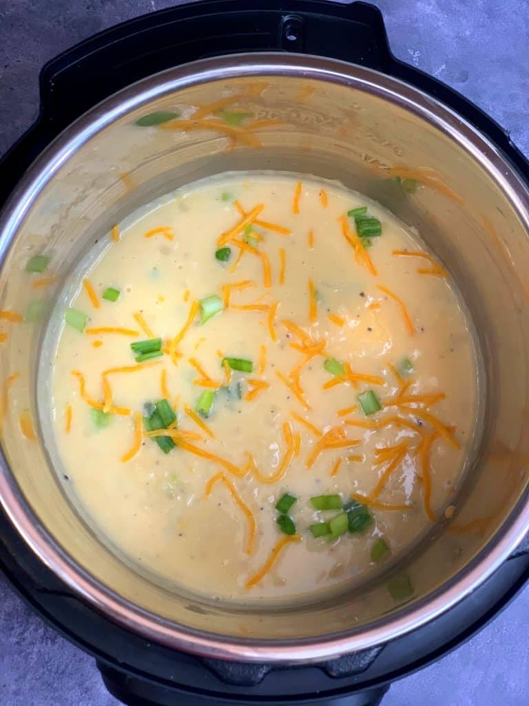 potato soup in instant pot insert garnished with green onions and cheddar cheese