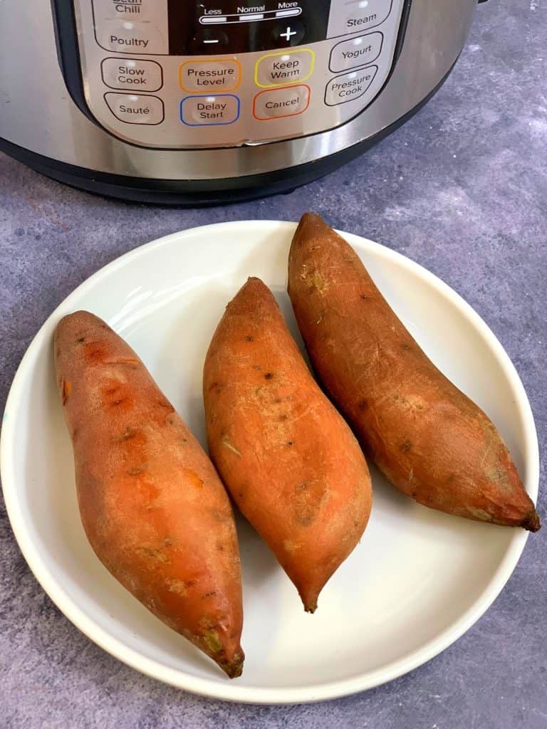 boiled/cooked sweet potatoes served in a white plate with instant pot on side