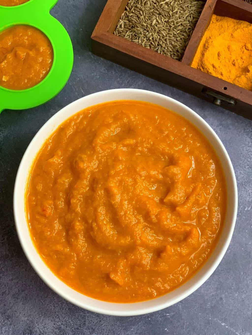 indian curry sauce in a white bowl and dry spices on side