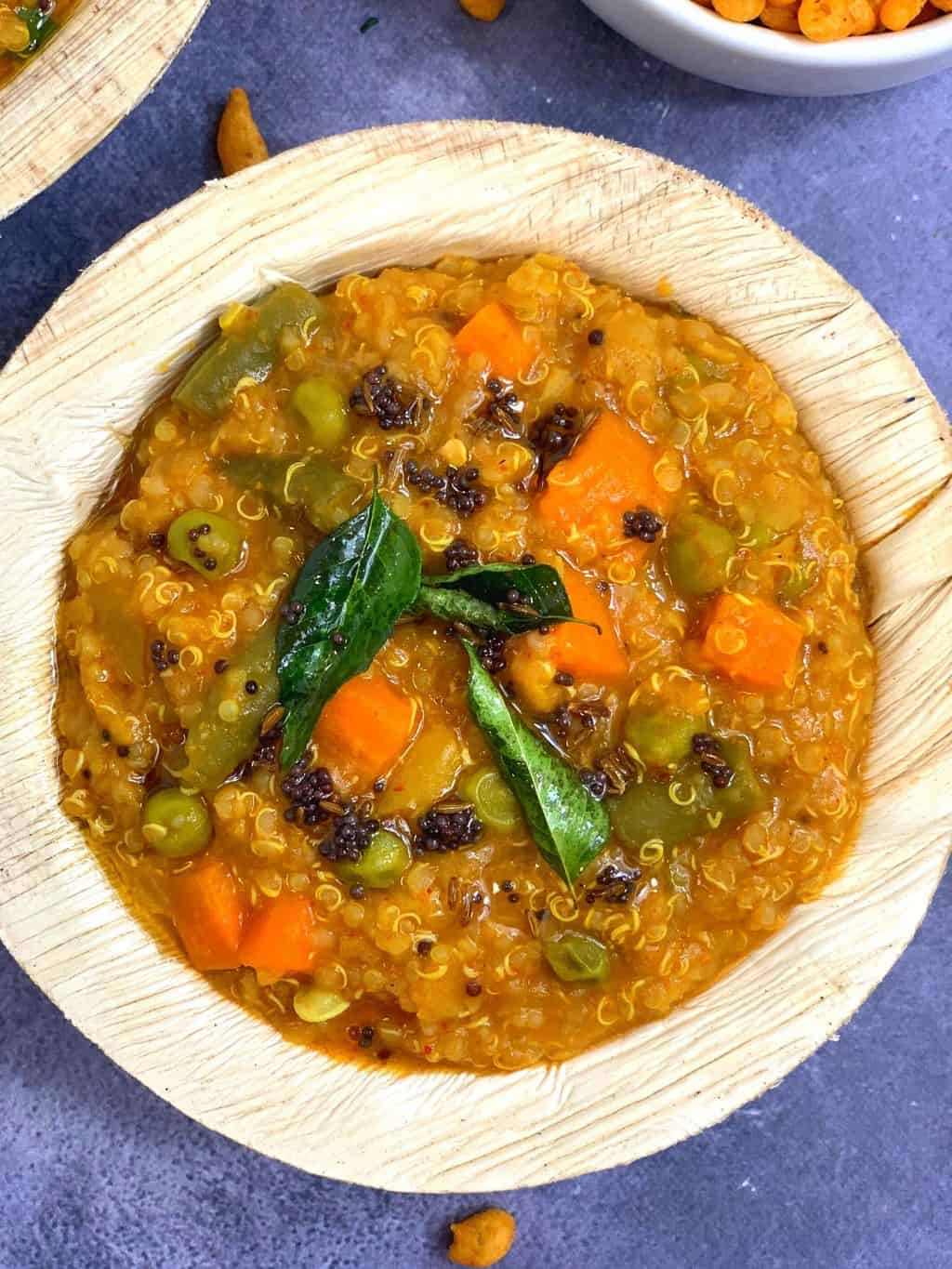 quinoa bisi bele bath served in a arekanut bowl with side of boondi