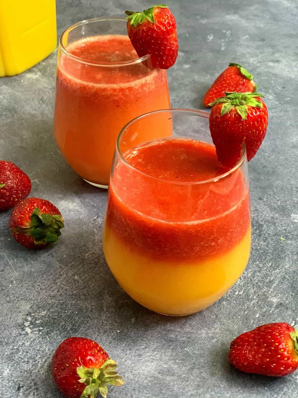 strawberry orange juice served in two glasses with strawberries on the side