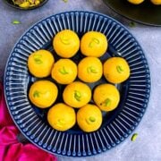 besan laddo served on a blue plate garnished with pistachios