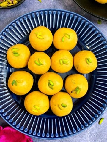 besan laddo served on a blue plate garnished with pistachios