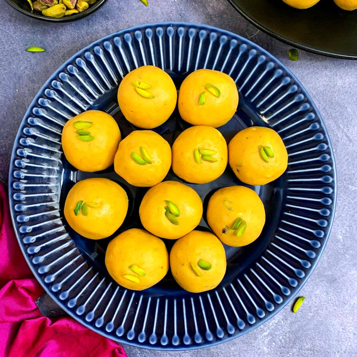 besan laddo served on a blue plate garnished with pistachios