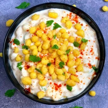 Boondi ka Raita served in a black bowl garnished with boondi and cilantro